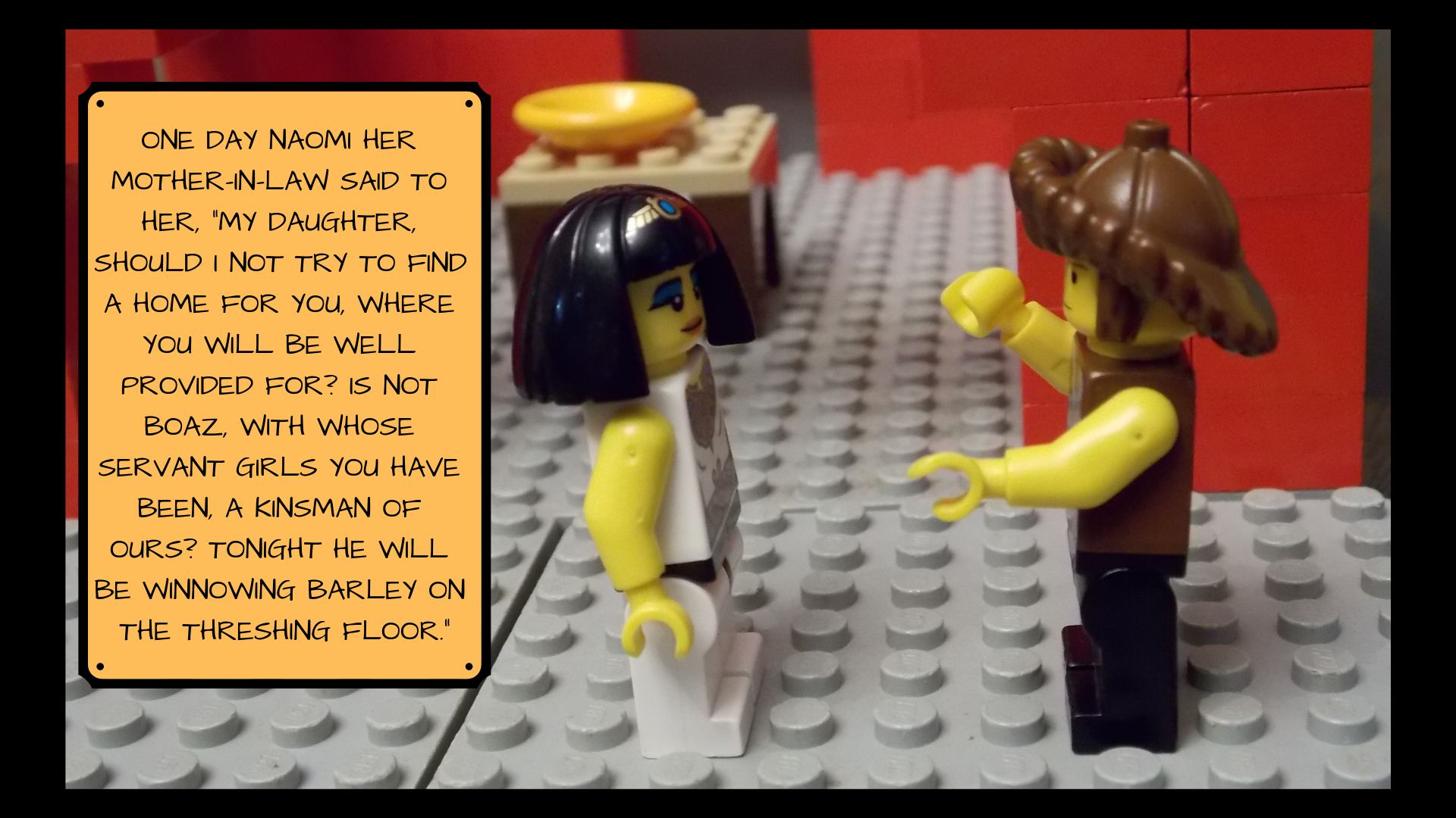 Lego Naomi talks with Lego Ruth with exaggerated arm gestures with the text, "One day Naomi her mother-in-law said to her, 'My daughter, should I not try to find a home for you where you will be well provided for? Is not Boaz, with whose servant girls you have been, a kinsman of ours? Tonight he will be winnowing barley on the threshing floor."